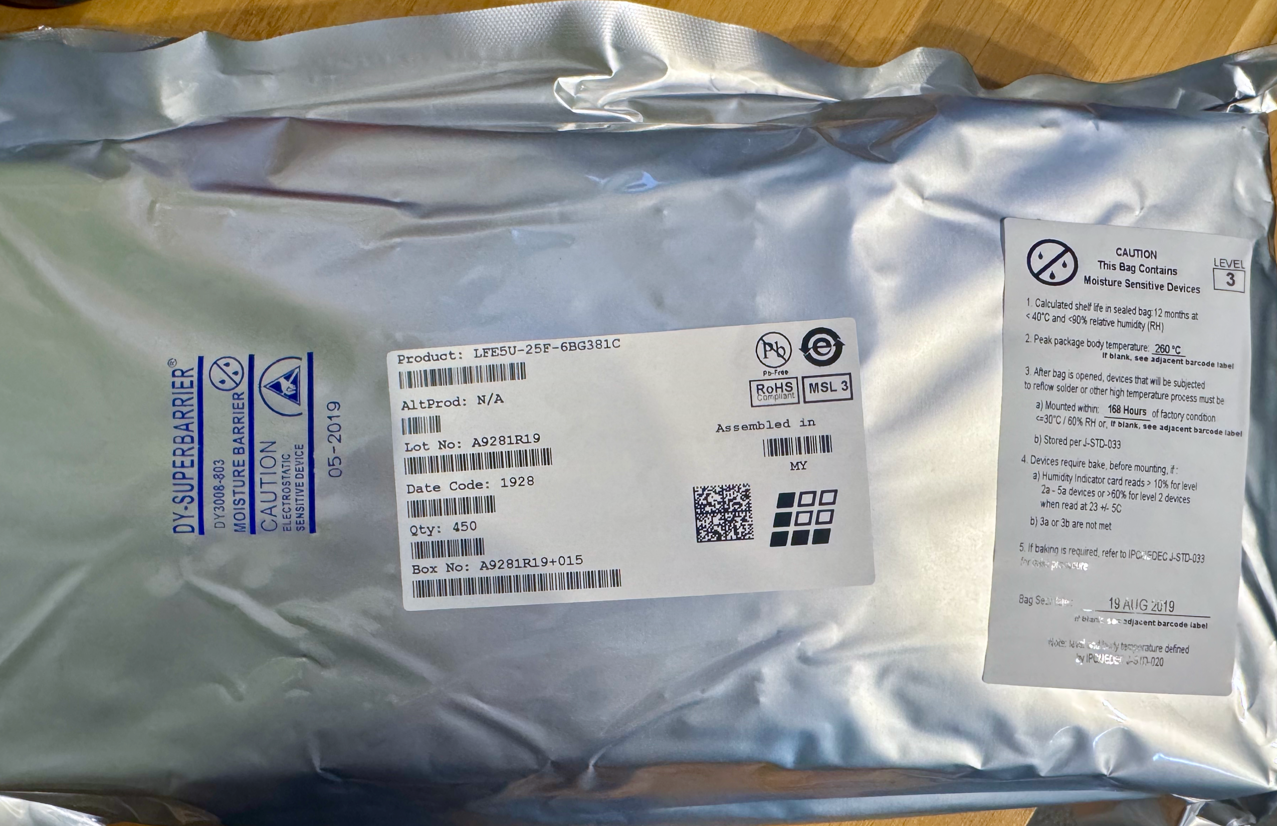 Sealed moisture barrier bag containing LFE5U-25F-6BG381C FPGA with manufacturer label showing date code 1928 and quantity 450